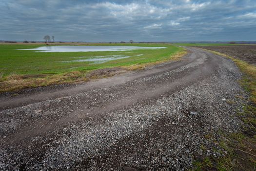 Gravel road in farmland and cloudy sky in Czulczyce, eastern Poland