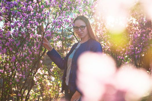 Woman travelling in Altai mountains on spring beautiful booming pink Rhododendron flowers background