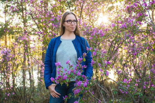 Woman travelling in Altai mountains on spring beautiful booming pink Rhododendron flowers background