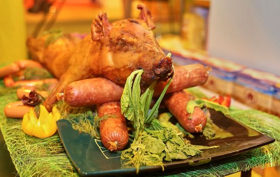 Grilled whole pig ready to serve. Sausage and a young pig on a platter.