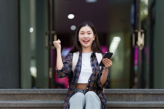 Young Beautiful woman using phone and celebrate while in victory position.