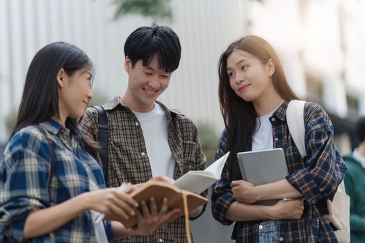 Beautiful young Asian woman college student with friends at outdoors. College student working on the college campus.