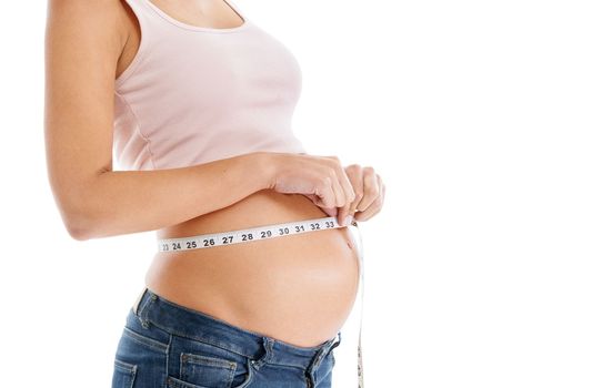 Charting the babies progress. A pregnant woman measuring her stomach with measuring tape - isolated