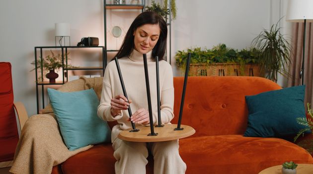 Happy brunette woman finishing assembling furniture at home. Successful table desk collect, repair fixing. Girl after moving into new apartment. Advertisement of a furniture store. Mortgage, lifestyle