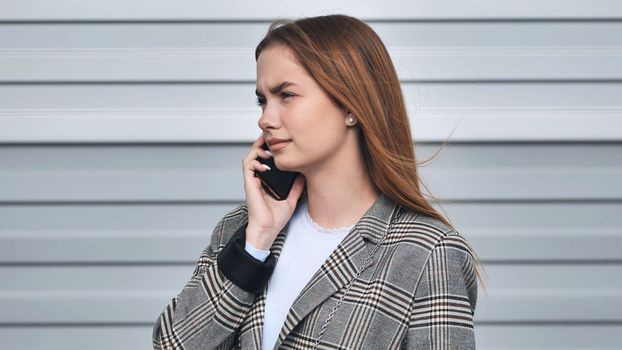 A student girl in a blazer talking on the phone