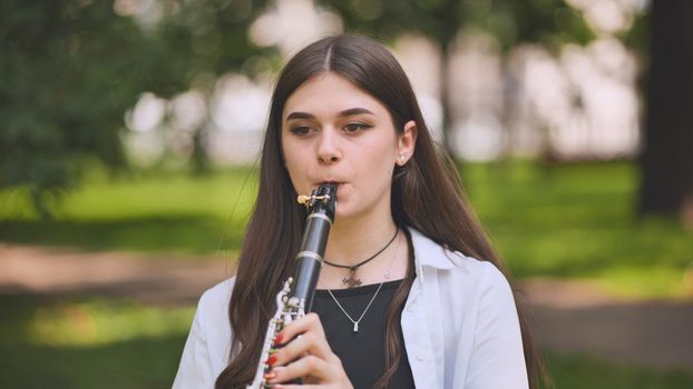 A girl plays the clarinet in the park