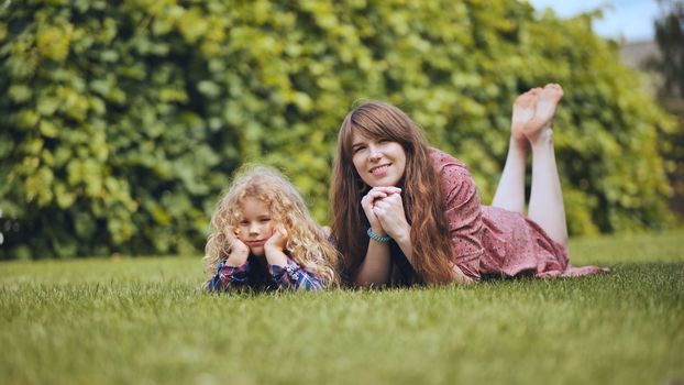 A mother and her daughter lie on the grass in the garden