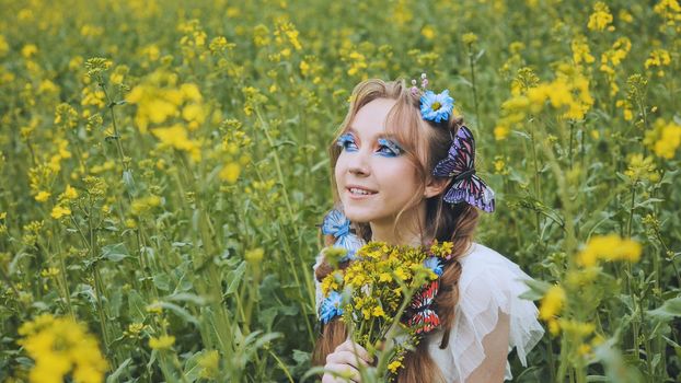 A young girl poses in a rapeseed field with a beautiful hairdo of flowers and butterflies