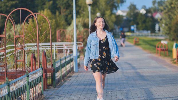 A cheerful girl walks along the city promenade