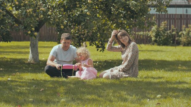 A young family on the grass in the garden outside their home