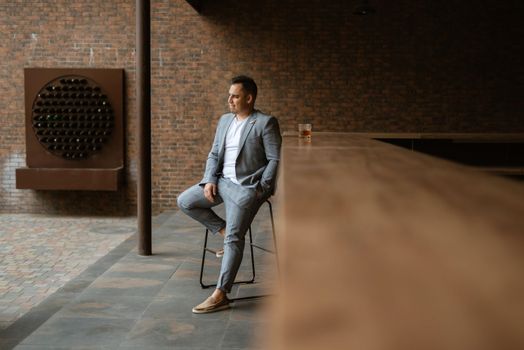 portrait of the groom in a light gray suit indoors