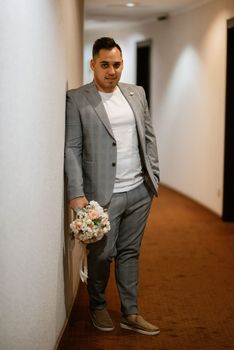 portrait of the groom in a light gray suit indoors