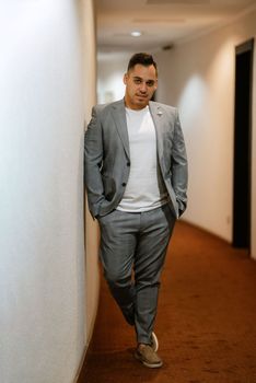 portrait of the groom in a light gray suit indoors