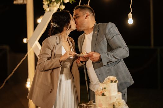 newlyweds happily cut, laugh and taste the wedding cake