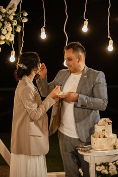 newlyweds happily cut, laugh and taste the wedding cake