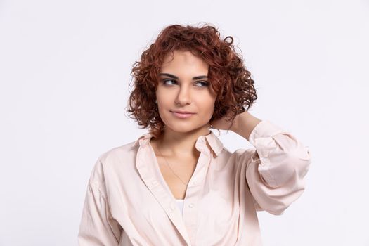 A gentle smile on her face. A European woman with chestnut-colored hair. A girl with fair skin and curly short hair looks straight ahead.