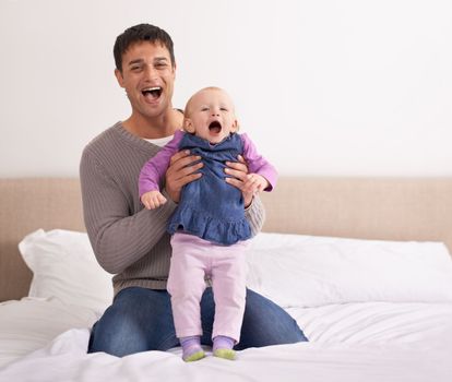 Theyre having so much fun together. A young father playing with his baby girl on the bed
