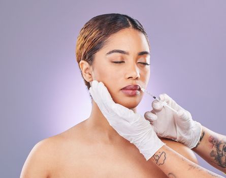 Beauty takes sacrifice. a young woman having her lips injected with filler against a pink background
