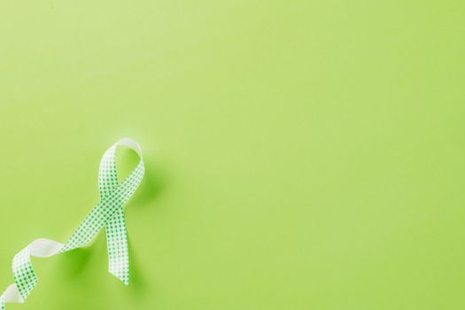 Green awareness ribbon of Gallbladder and Bile Duct Cancer month isolated on green background with copy space, concept of medical and health care support