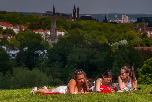 London - May 21, 2019 - Girls resting on a bright day at Hampstead Heath with a beautiful backdrop of the city.