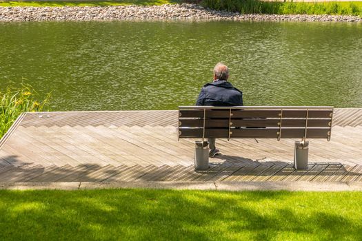 London 7 Jun 62 - Alone man sits leg over on bench beside the swamp,  Men relax and watch the water in the marsh.