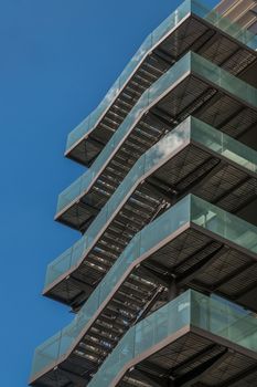 London 6 Jun 62 - Business building with metal emergency ladder / fire escape in modern office buildings with repeating structure and reflected sky and clouds.