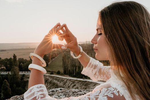 Romantic beautiful bride in white dress posing with sea and mountains in background. Stylish bride standing back on beautiful landscape of sea and mountains on sunset