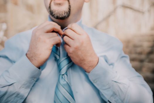 Close up of Man Adjusting Tie of Suit. Businessman in white shirt straightens his tie, close-up.