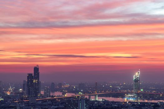 Bangkok, thailand - Dec 23, 2020 : Aerial view of Bangkok city Overlooking Skyscrapers and the Bridge crosses the Chao Phraya river with bright glowing lights at dusk. No focus, specifically.