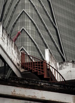 Bangkok, thailand - Mar 18, 2022 : Architectural View of Overlapping Modern high building exterior and Old house buildings with Red iron spiral staircase an points of interest. Focus and blur.