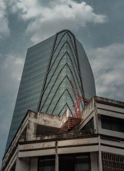 Bangkok, thailand - Mar 18, 2022 : Architectural View of Overlapping Modern high building exterior and Old house buildings with Red iron spiral staircase an points of interest. Selective focus.