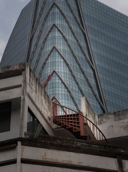 Bangkok, thailand - Mar 18, 2022 : Architectural View of Overlapping Modern high building exterior and Old house buildings with Red iron spiral staircase an points of interest. No focus, specifically.