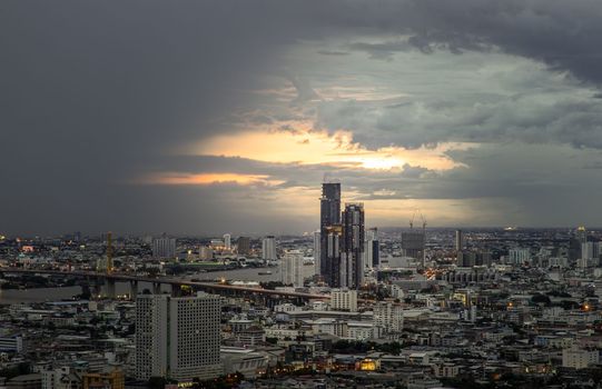 Bangkok, Thailand - 07 Jul 2021 : Aerial view of Beautiful sunset over large metropol city in Asia. There are prominent and isolated high-rise buildings along the Chao Phraya River. Selective focus.