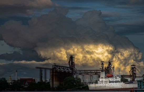 Bangkok, Thailand - 11 Jul 2021 : A cargo ship parked in front of Petroleum refinery on the Chao Phraya River in the evening. No focus, specifically.