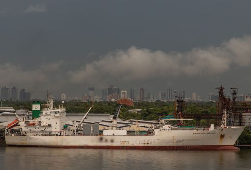Bangkok, Thailand - Jun 17, 2020 : Cargo ships are floating over the Chaopraya river. They are waiting to be docked at pier.
