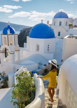 Happy Asian woman visit Oia Santorini Greece on a sunny day during summer with whitewashed homes and churches, Greek Island Aegean Cyclades