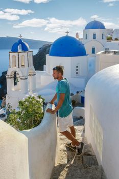 Young men tourists visit Oia Santorini Greece on a sunny day during summer with whitewashed homes and churches, Greek Island Aegean Cyclades