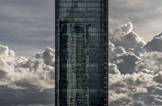 Bangkok, Thailand - Sep 24, 2020 : Angular geometric mirror cladding on a modern building with repeating structure and reflected sky and clouds. No focus, specifically.