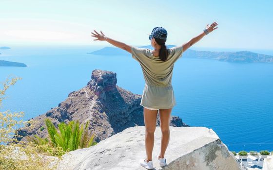 Happy Asian woman visit Oia Santorini Greece on a sunny day during summer with whitewashed homes and churches, Greek Island Aegean Cyclades