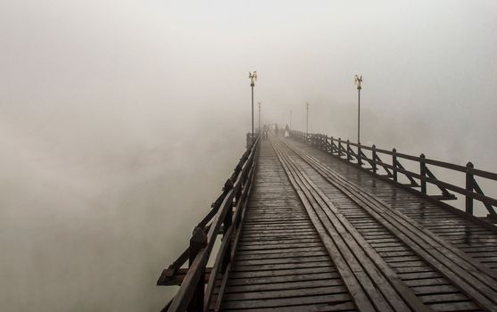 Mon wood bridge in the morning in the fog down (Sangkhla Buri, Kanchanaburi, Thailand) This Mon wood bridge is officially named Uthamanusorn Bridge. No focus, specifically.