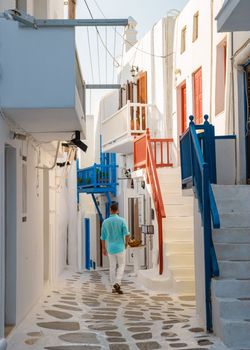 Young men visit Mykonos Greek village in Greece, with colorful streets of Mikonos village.