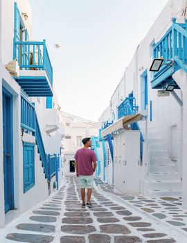 Young men visit Mykonos Greek village in Greece, with colorful streets of Mikonos village.