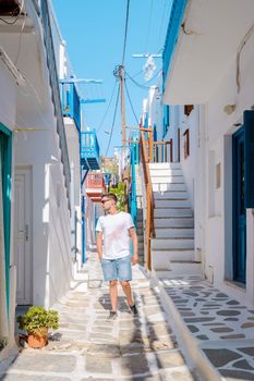 Young men visit Mykonos Greek village in Greece, with colorful streets of Mikonos village.
