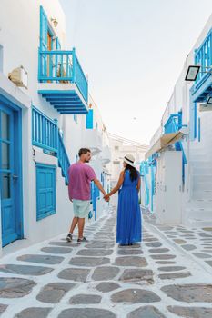 Romantic couple of men and women at the street of Mykonos Greek village in Greece, colorful streets of Mikonos village.in the morning