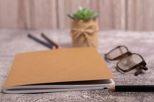 closed notebook with brown covers, pencil, glasses and coffee cup with copy space