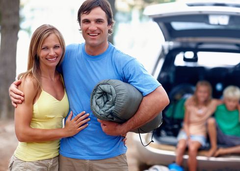 Couple enjoying holiday with kids. Portrait of couple enjoying their holiday with kids sitting in car