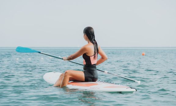 Sea woman sup. Silhouette of happy young woman in pink bikini, surfing on SUP board, confident paddling through water surface. Idyllic sunset. Active lifestyle at sea or river. Slow motion