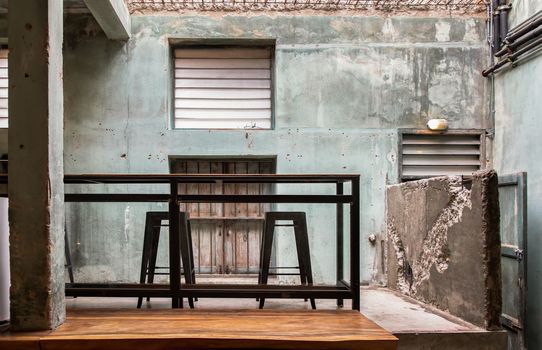Interior design and decoration with table and two chairs at the background is the old concrete wall.  No focus, specifically.