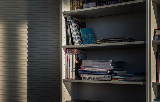 Bangkok,Thailand - Jan 10, 2022 : Library of shared facility at living room of home condominium. Different books are arranged on a white bookshelf, No focus, specifically.