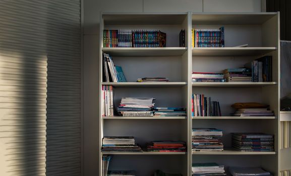 Bangkok,Thailand - Jan 10, 2022 : Library of shared facility at living room of home condominium. Different books are arranged on a white bookshelf, No focus, specifically.